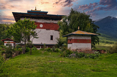 House on field by building against sky