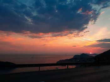 Scenic view of sea against dramatic sky during sunset