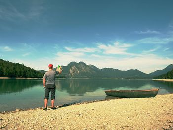 Taveler is taking memory photo of lake scenery. lake between high mountains, peaks touch in blue sky