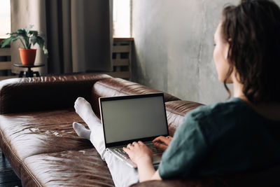 Digital connectivity and productivity. young woman utilizes laptop with blank white screen at home