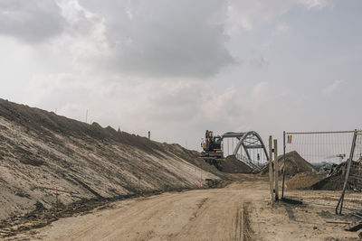 Road by factory against sky