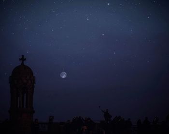 Low angle view of silhouette building against sky at night