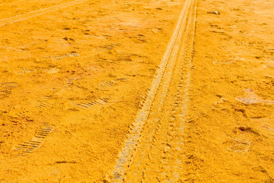 Yellow powder paint with footprint and tire track on road