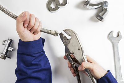 Cropped hands of man holding hand tools on white table