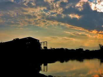 Silhouette of bridge over river at sunset