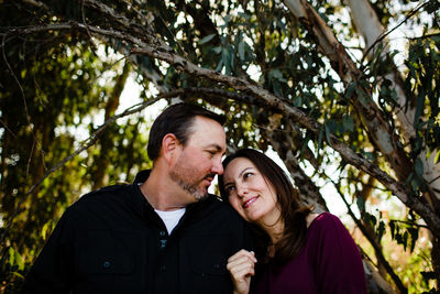 Portrait of couple kissing against trees