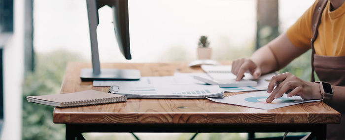 Midsection of woman using laptop on table