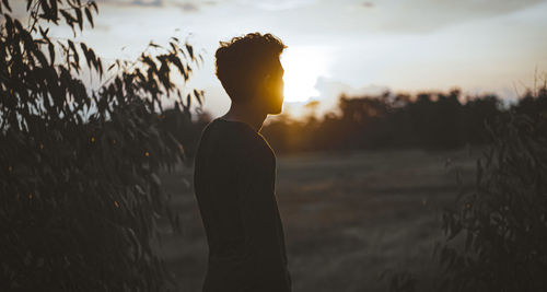 Side view of man standing against sky during sunset