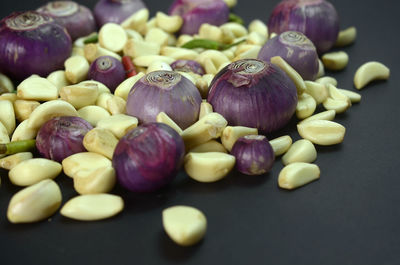 A mixture of cooking ingredients such as peeled garlic,onions and chili on a black background