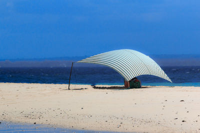 Lifeguard hut on beach against clear blue sky