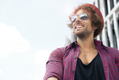 Portrait of young man wearing sunglasses standing against sky