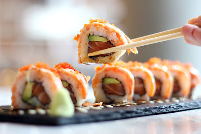 Cropped image of person holding sushi at table