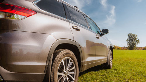 Rear side of gray car driving on the road with background of grass and country city. 