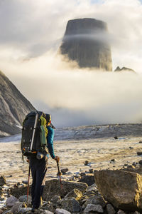 Backpacker looking up at the summit of mount asgard, baffin island.