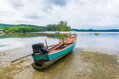 Boat moored on beach against sky