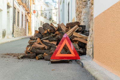 Pieces of firewood piled on the door of a house, with a red caution sign in front.