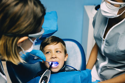 Dentist operating boy in medical clinic