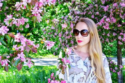 Beautiful woman with long hair standing by flowering trees