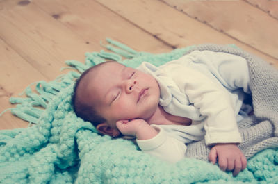 Close-up of cute baby boy sleeping on hardwood floor