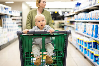 Portrait of cute boy with toy shopping cart in supermarket