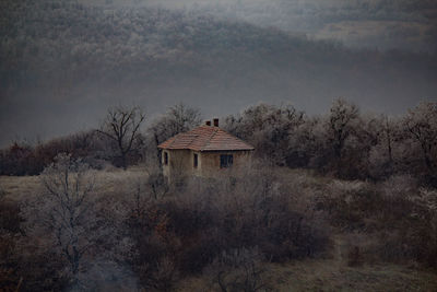 House on field by trees against sky