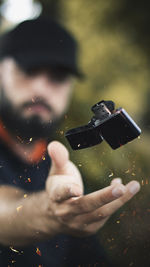 Young man catching cigarette lighter while standing outdoors