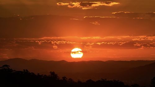 Scenic view of silhouette mountains against romantic sky at sunset