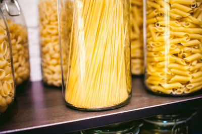 Close-up of raw pastas in jars on store shelves for sale