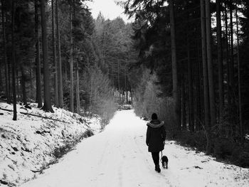 Rear view of woman walking on snow covered road