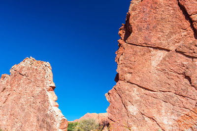 Low angle view of rock formations against clear blue sky