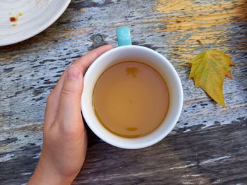 Hand of person holding tea on table