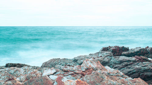 Scenic view of rocks by sea against sky