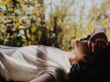 Side view of young man lying in forest