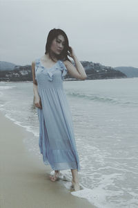 Young woman standing on beach against sky