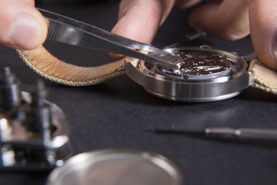 Cropped hand of craftsperson repairing wristwatch at desk