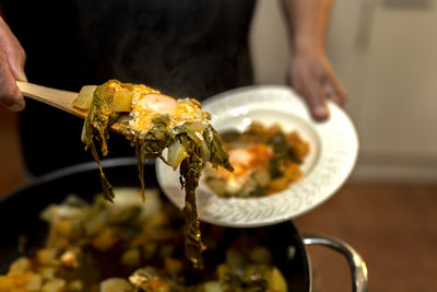 Male hand serving a portion of chard acquacotta egg. 