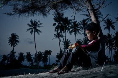 Woman sitting on land against trees