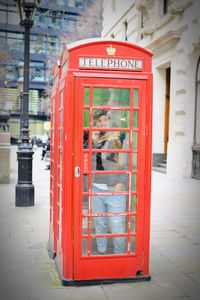 Red telephone booth on sidewalk in city