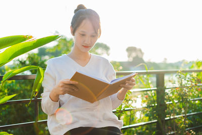 Portrait of young woman standing against trees