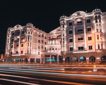 Light trails on road against buildings at night