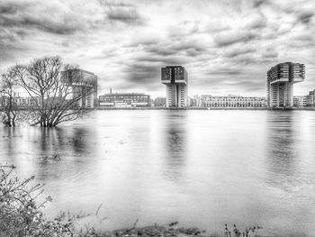 Buildings by river against sky in city