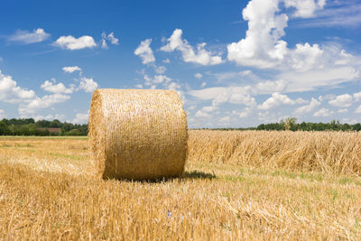 Hay bales on field against sky