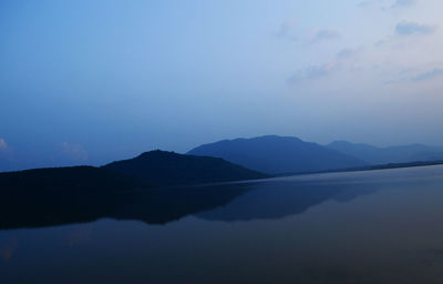 Scenic view of lake by silhouette mountains against sky