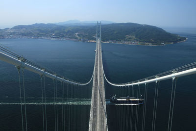 High angle view of suspension bridge over boat sailing in sea