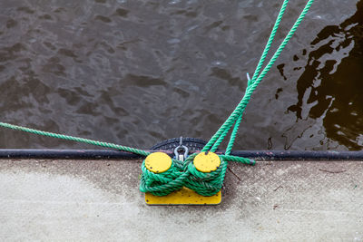 High angle view of rope tied to moored at harbor