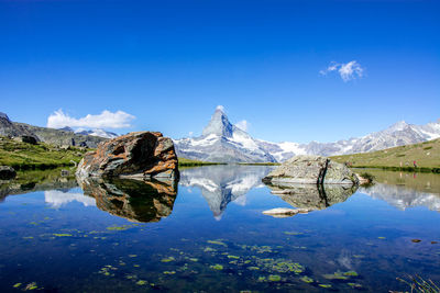 Scenic view of lake and mountains against blue sky