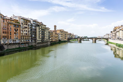 Ponte santa trinita over arno river amidst buildings against sky