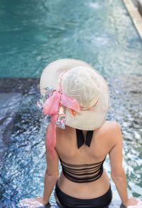 Rear view of woman with hat on swimming pool