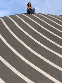 Portrait of woman sitting on zebra crossing