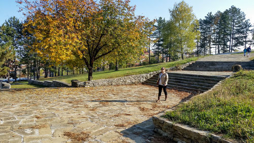 Boy walking on retaining wall against trees